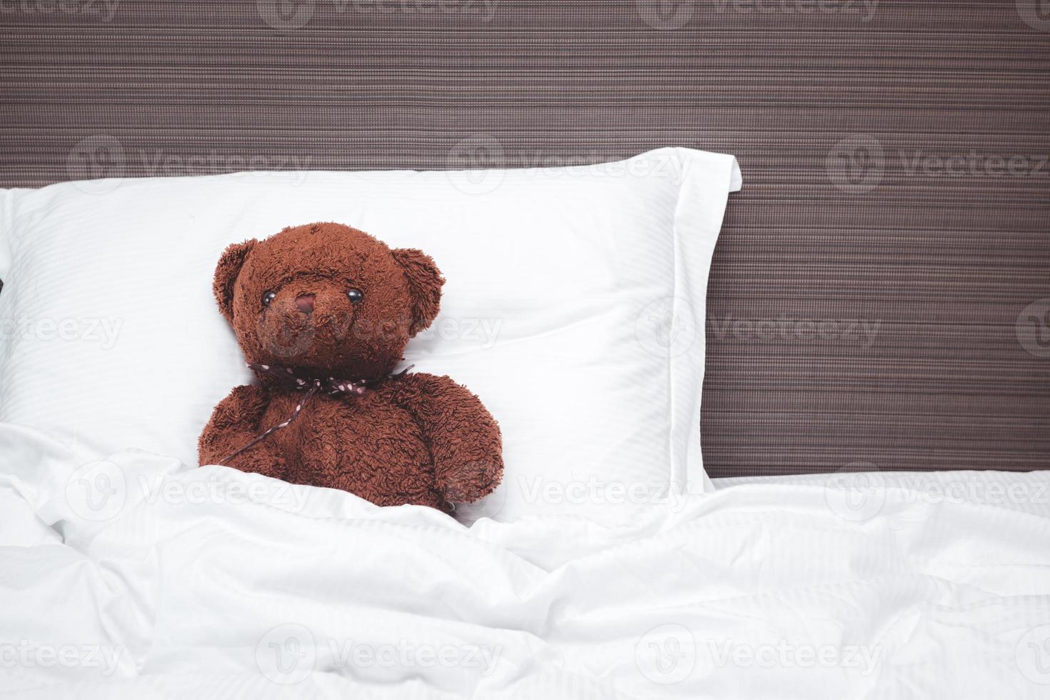 Old brown teddy bear sleep on pillow, rest and relax. photo