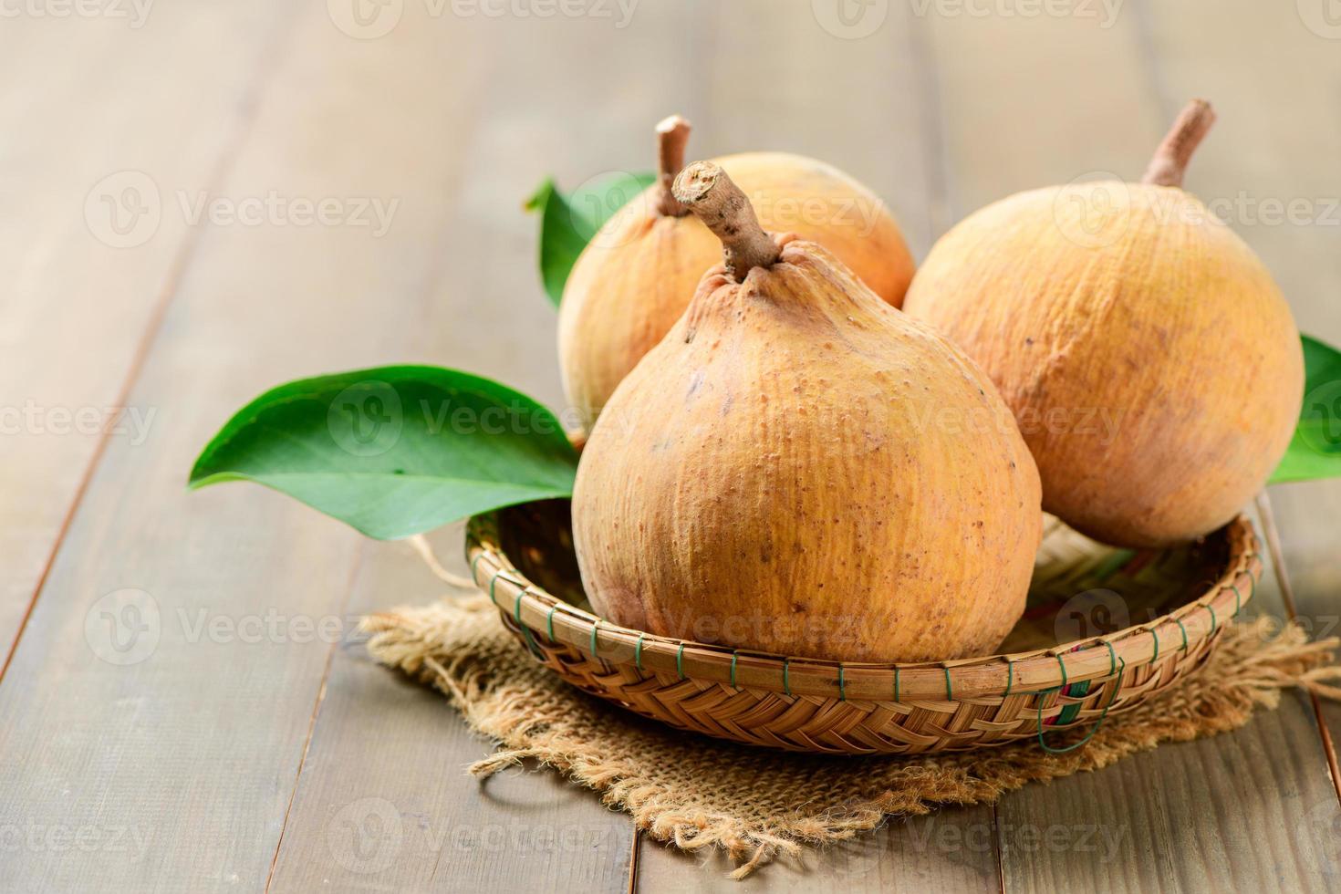 Santol fruits in bamboo basket on wood background, photo