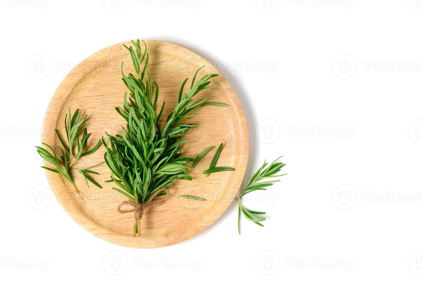 Branch of fresh rosemary on wood plate isolated on white  background. photo