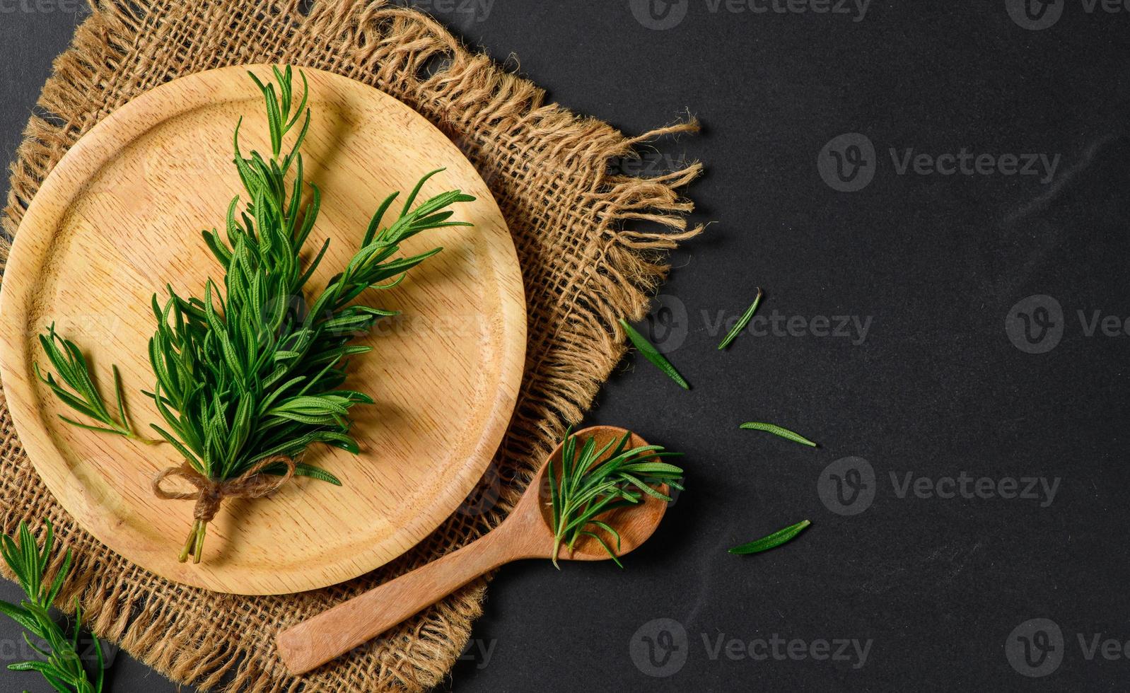 Top view of Branch fresh rosemary in wood plate on black  background. photo