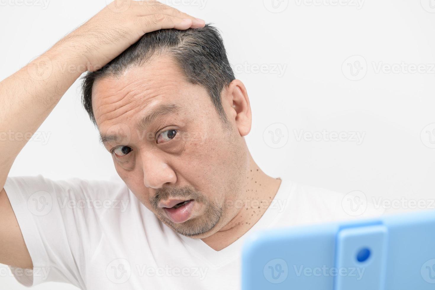 A middle-aged man shines in the mirror and worry about hair loss or hair gray  isolated photo