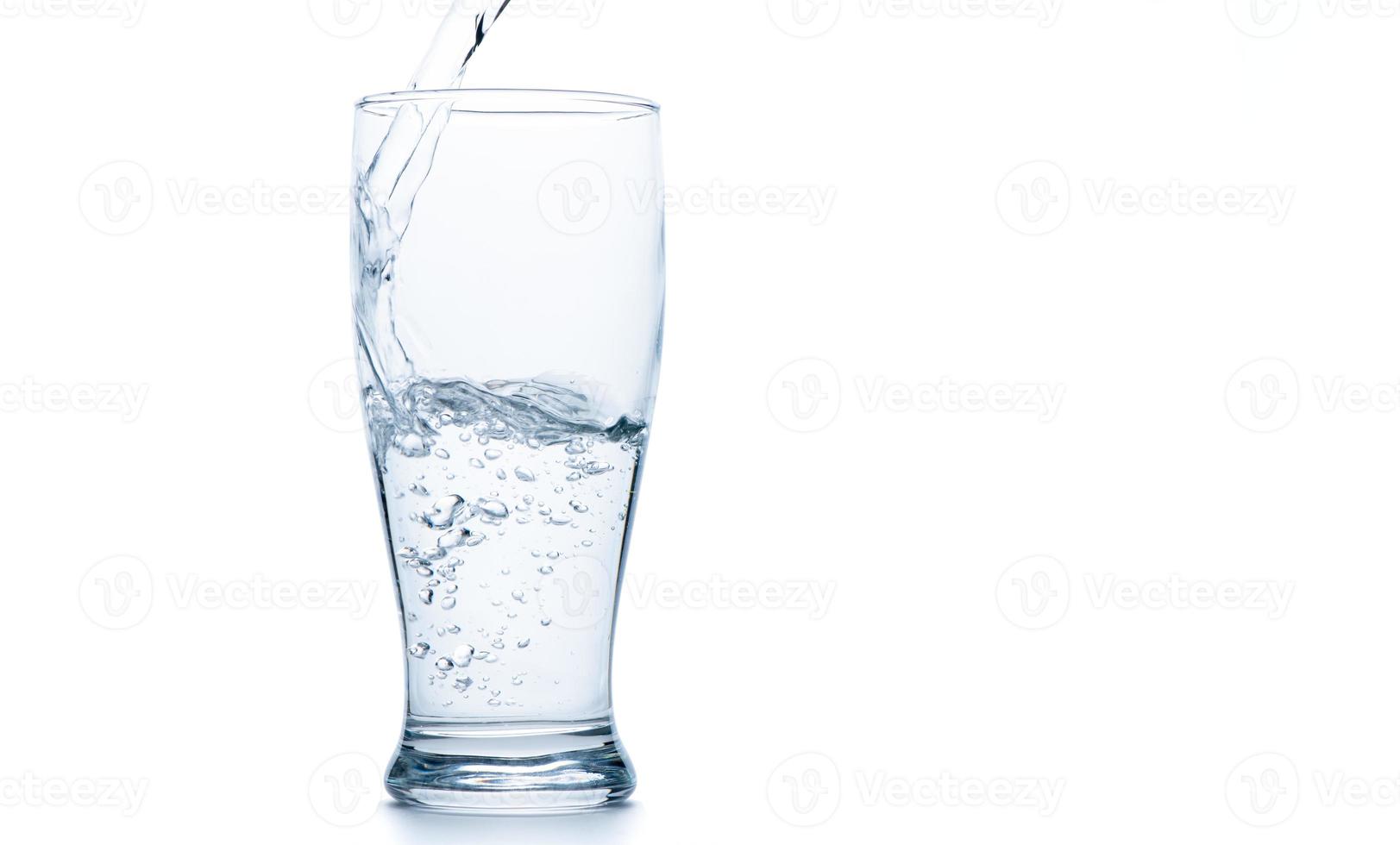 Water pouring into the clear Pilsner glass isolated on white photo