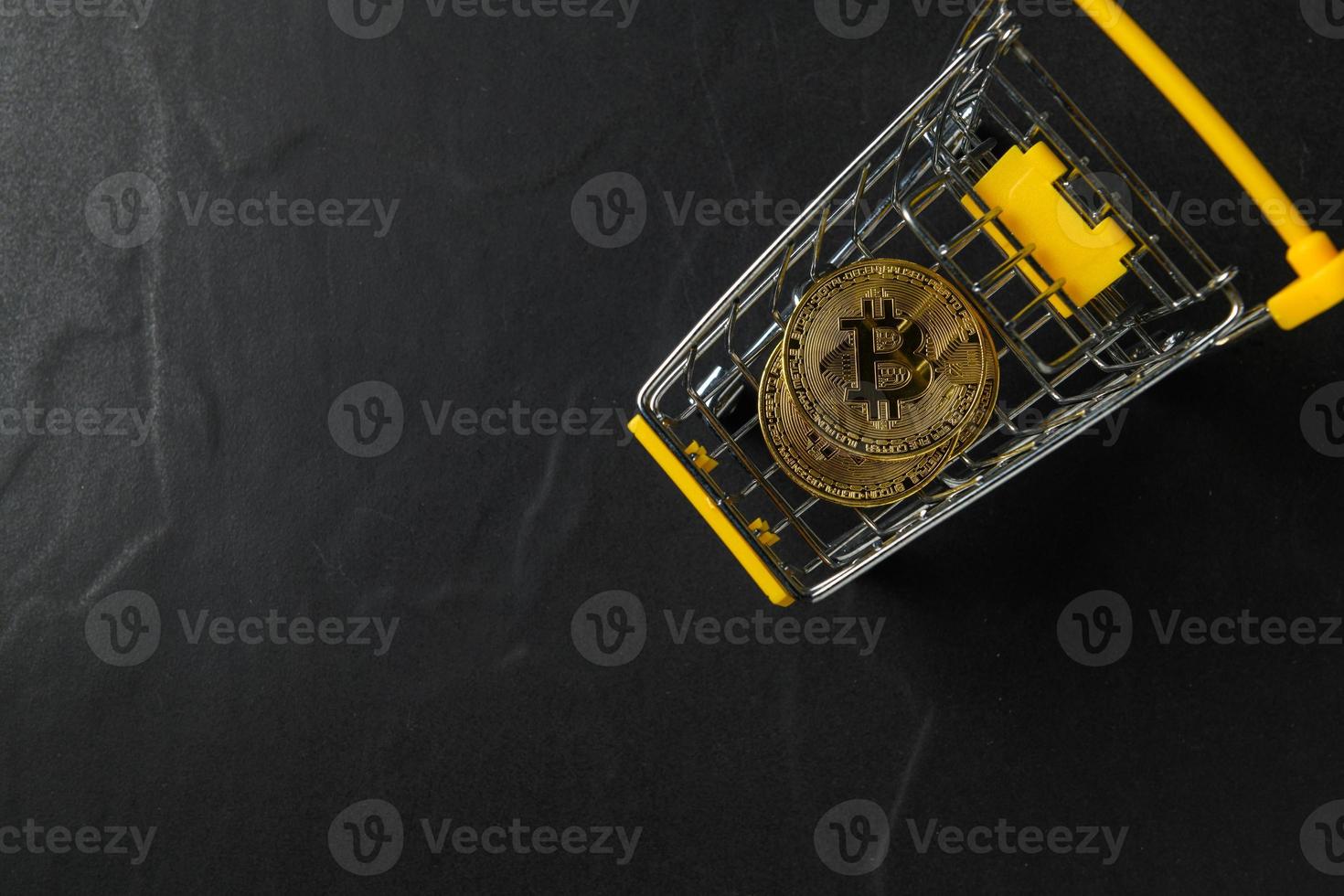 bit coin in yellow trolley on black background and top view, electronic virtual money for web banking and international network payment photo