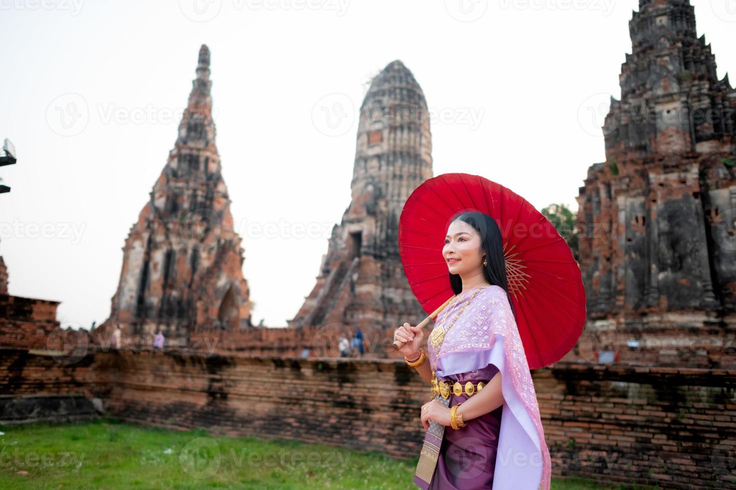 Beautiful Thai girl in traditional dress costume red umbrella as Thai temple where is the public place, Thai Woman in Traditional Costume of Thailand. photo