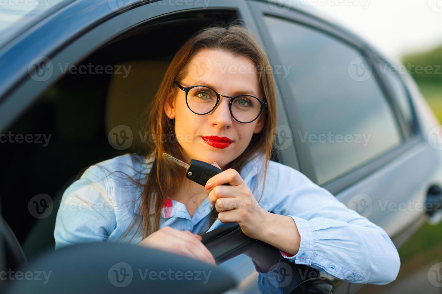 joven bonito mujer sentado en un coche con el llaves en mano foto