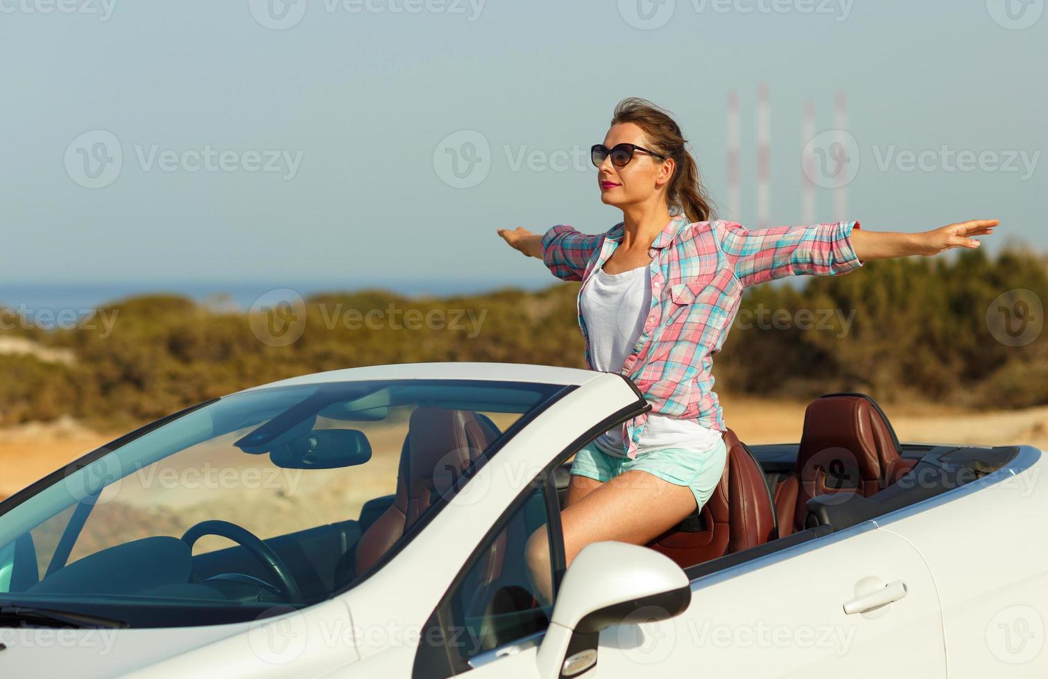 hermosa mujer sentado en cabriolé, disfrutando viaje en lujo moderno coche con abierto techo foto