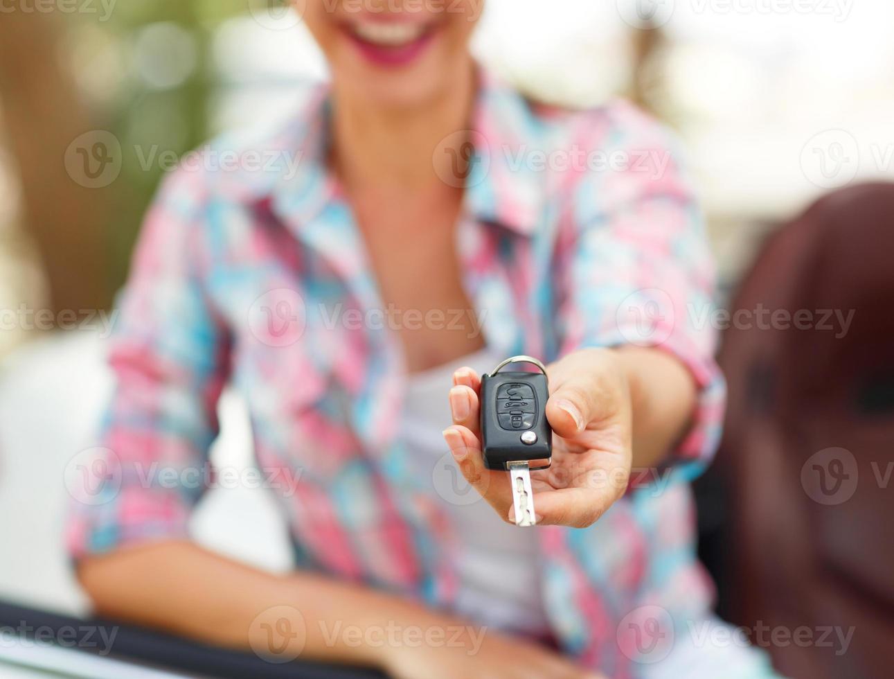 Young woman standing near a convertible with keys in hand photo