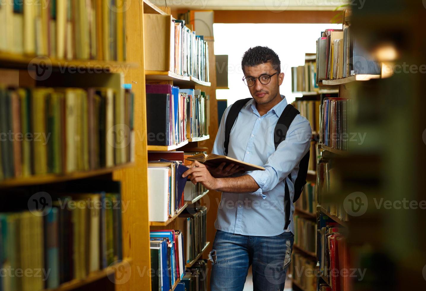 Student reading book between the shelves in the library photo