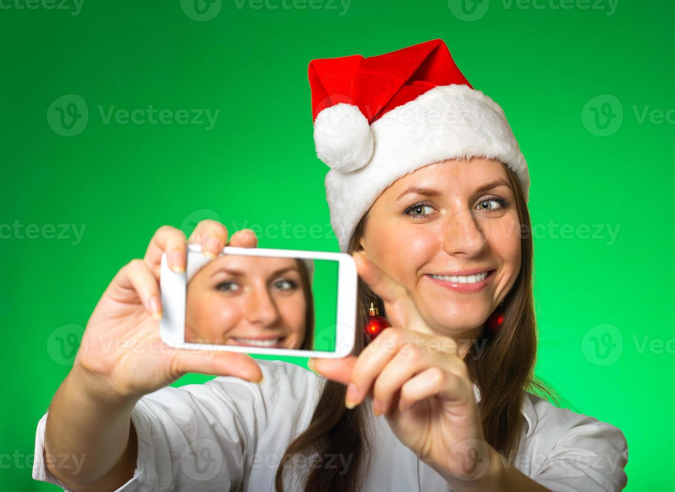 Girl in a Christmas hat on a green background photo