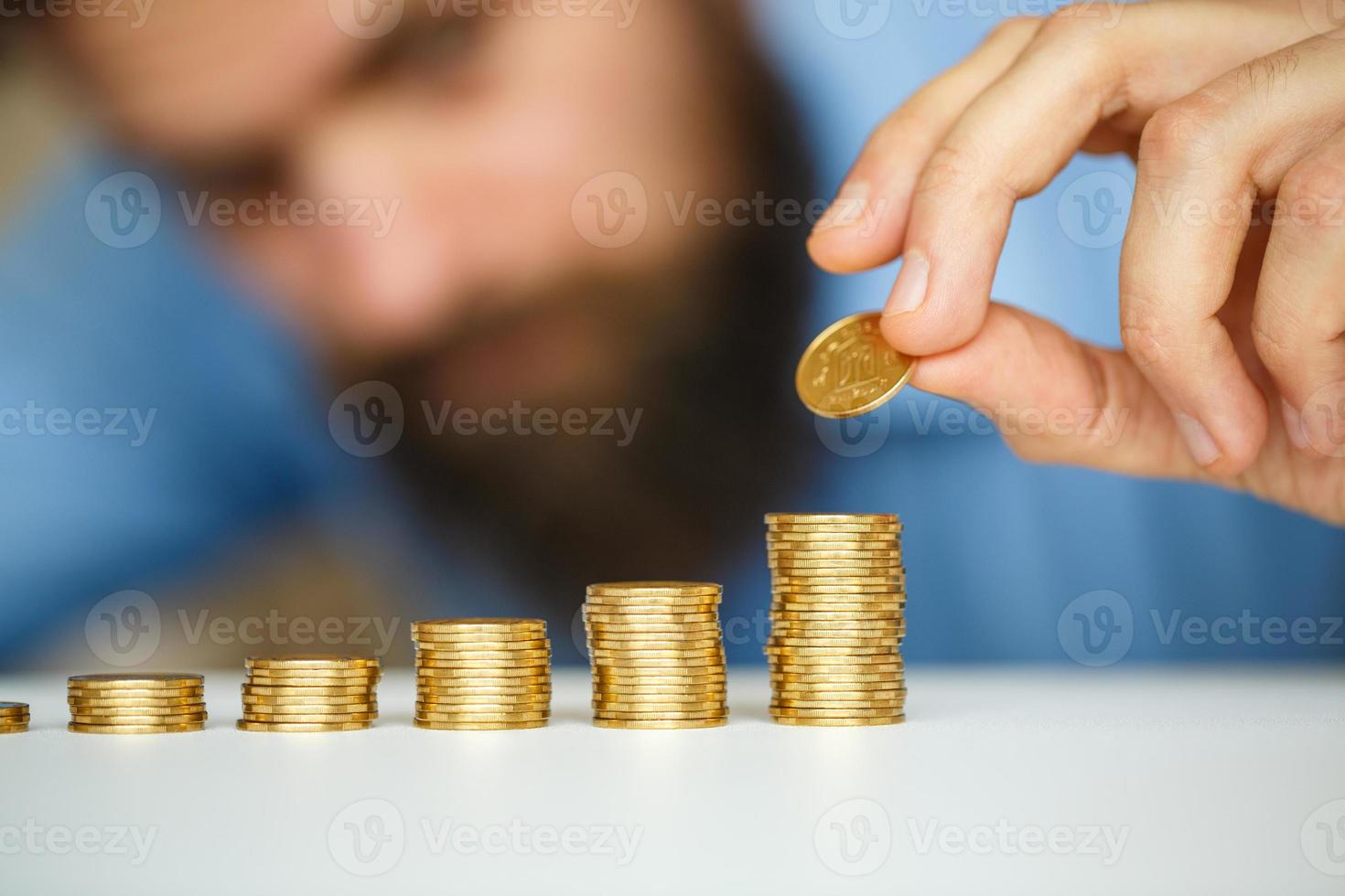 Business man stacking gold coins into increasing columns photo