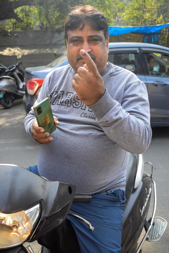 New Delhi, India - December 04 2022 - Unidentified people showing their ink-marked fingers after casting votes in front of polling booth of east Delhi area for MCD local body Elections 2022 photo