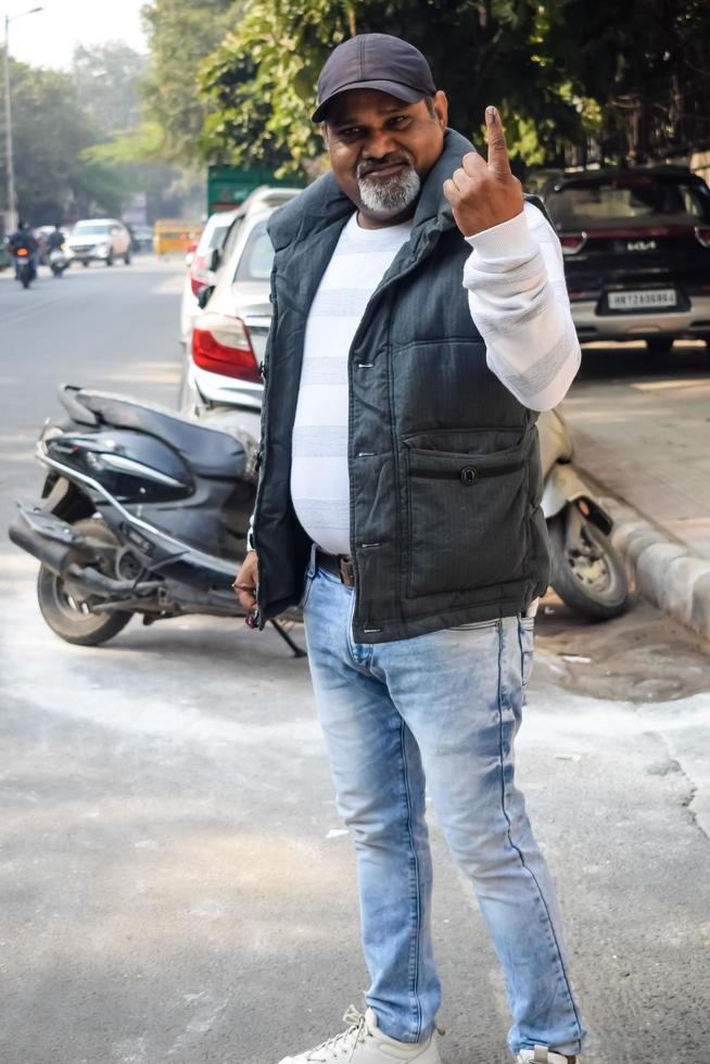 New Delhi, India - December 04 2022 - Unidentified people showing their ink-marked fingers after casting votes in front of polling booth of east Delhi area for MCD local body Elections 2022 photo