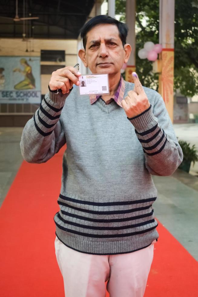 New Delhi, India - December 04 2022 - Unidentified people showing their ink-marked fingers after casting votes in front of polling booth of east Delhi area for MCD local body Elections 2022 photo