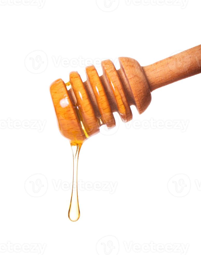 Honey dripping from a wooden dipper photo