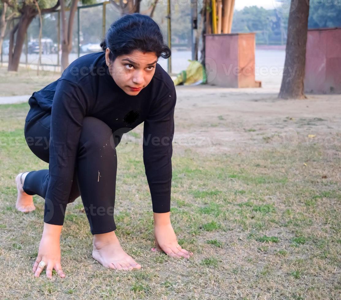 joven india practicando yoga al aire libre en un parque. hermosa chica practica pose básica de yoga. calma y relax, felicidad femenina. posturas básicas de yoga al aire libre foto