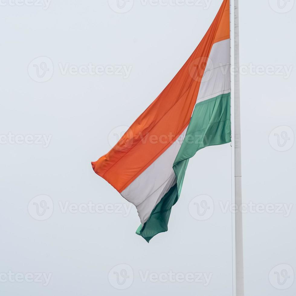 India flag flying high at Connaught Place with pride in blue sky, India flag fluttering, Indian Flag on Independence Day and Republic Day of India, tilt up shot, Waving Indian flag, Har Ghar Tiranga photo