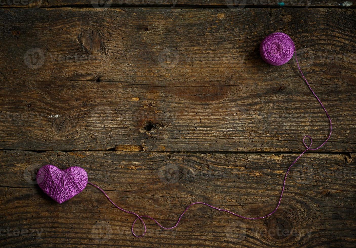 Purple Heart with a ball of thread on on old shabby wooden background photo