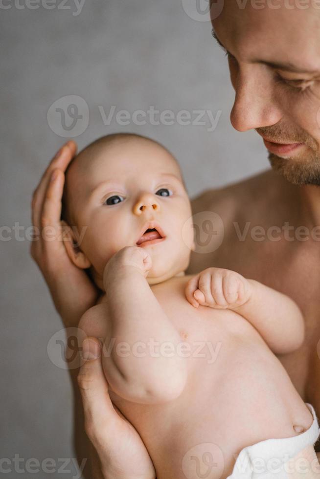 Happy Caucasian father holds his baby son in his arms and looks at him with care and love photo