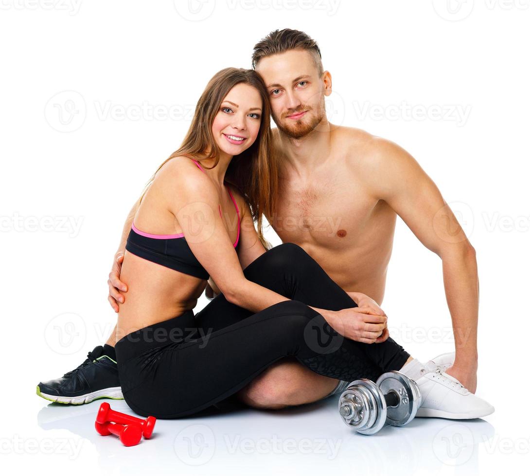 Sport couple - man and woman after fitness exercise sitting with dumbbells on the white photo