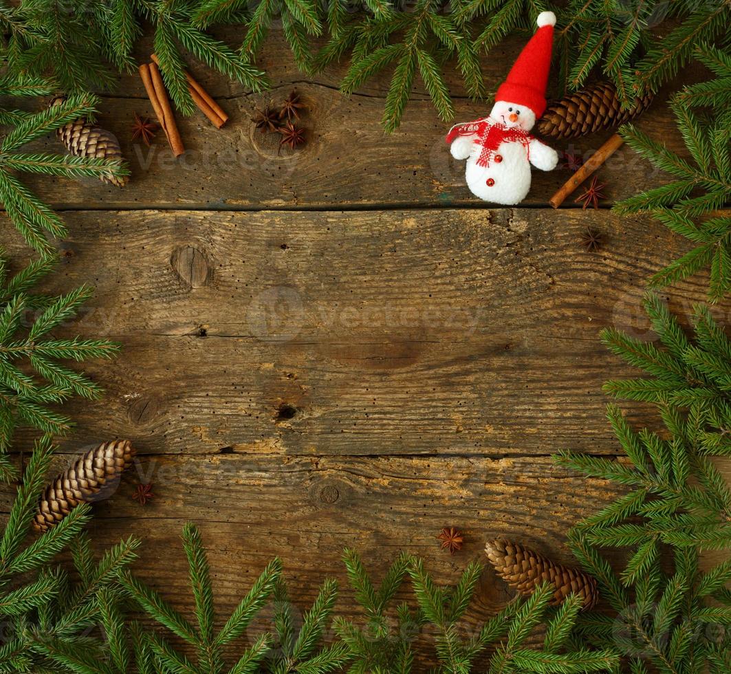 Christmas tree branch with cones, cinnamon, dittany and snowman on wooden background with copyspace photo