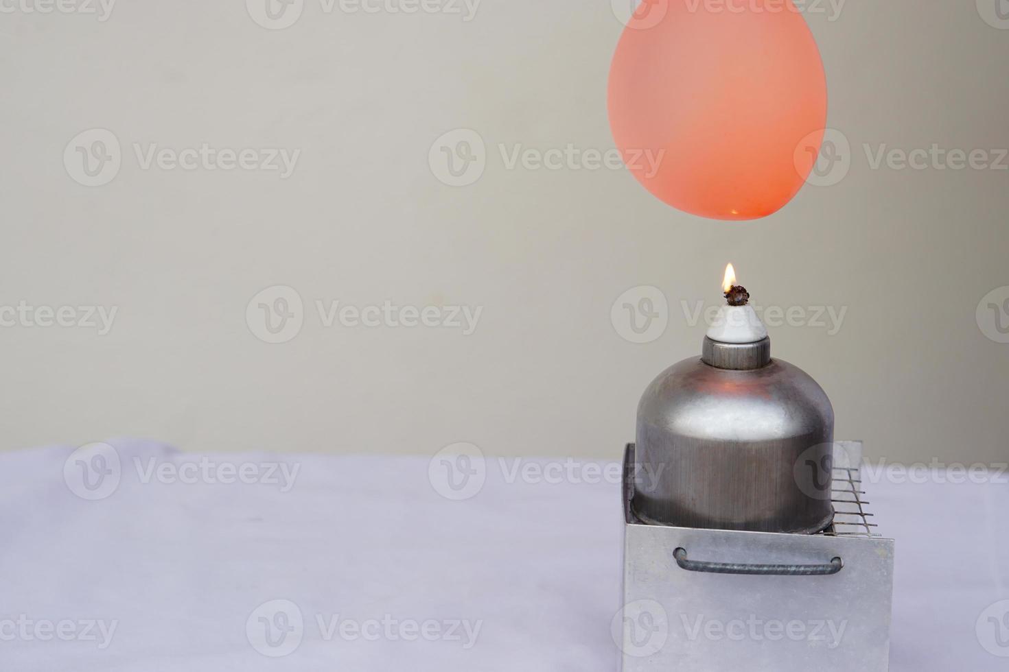 Balloon with water filled is burned on fire flame of metal lantern. Concept, science experiment. Fireproof balloon demonstration. Balloon with water inside doesn't pop under flame. photo