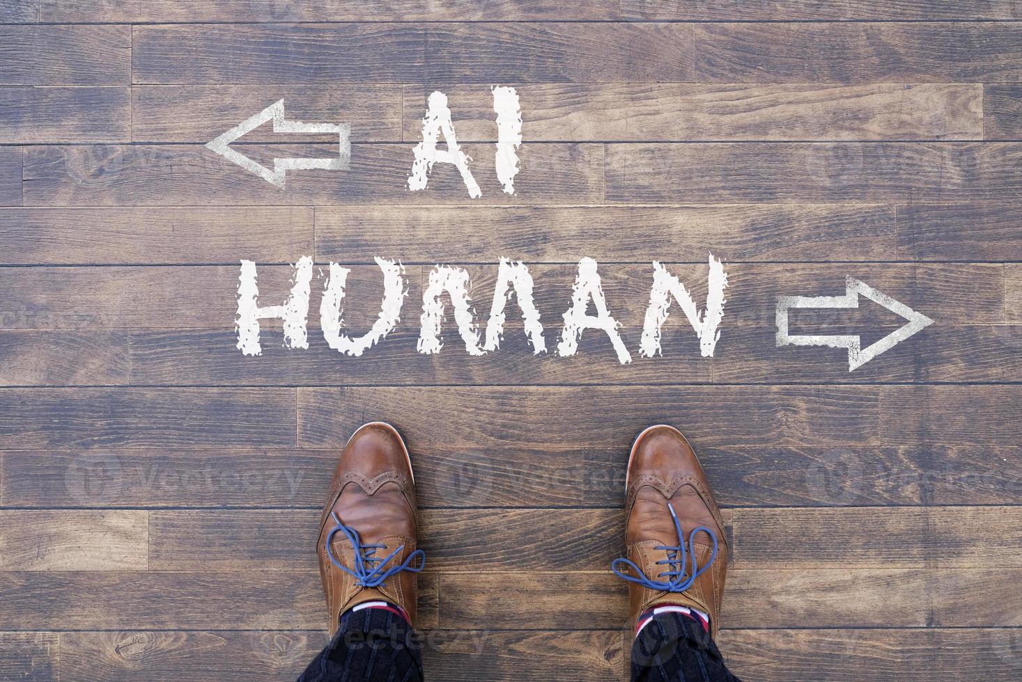 Man looking down at the words Artificial Intelligence - AI - and Human chalked onto the floor photo