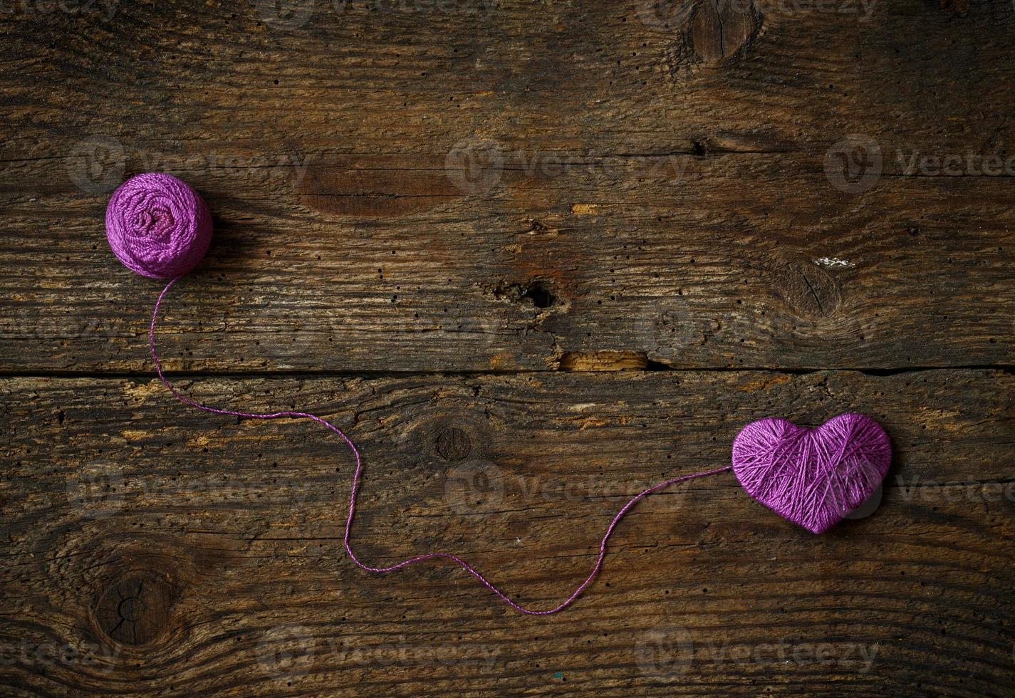 Purple Heart with a ball of thread on on old shabby wooden background photo