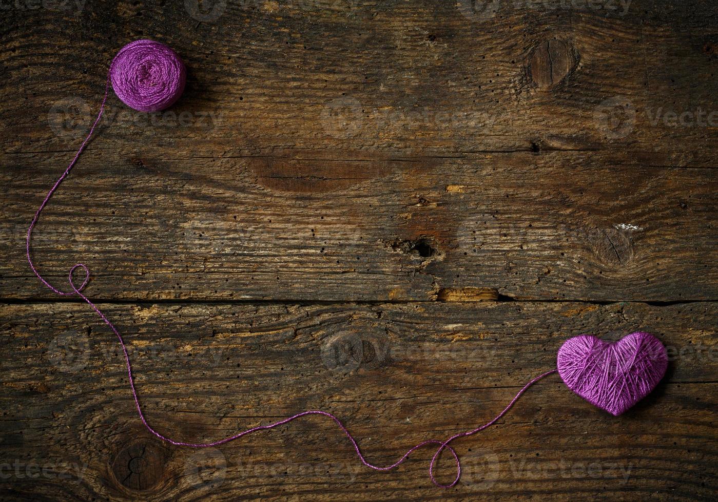 Purple Heart with a ball of thread on on old shabby wooden background photo