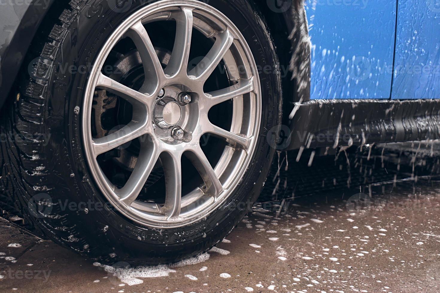 Hand wash with soap, pink foam on the body. Car washing with high pressure water. photo