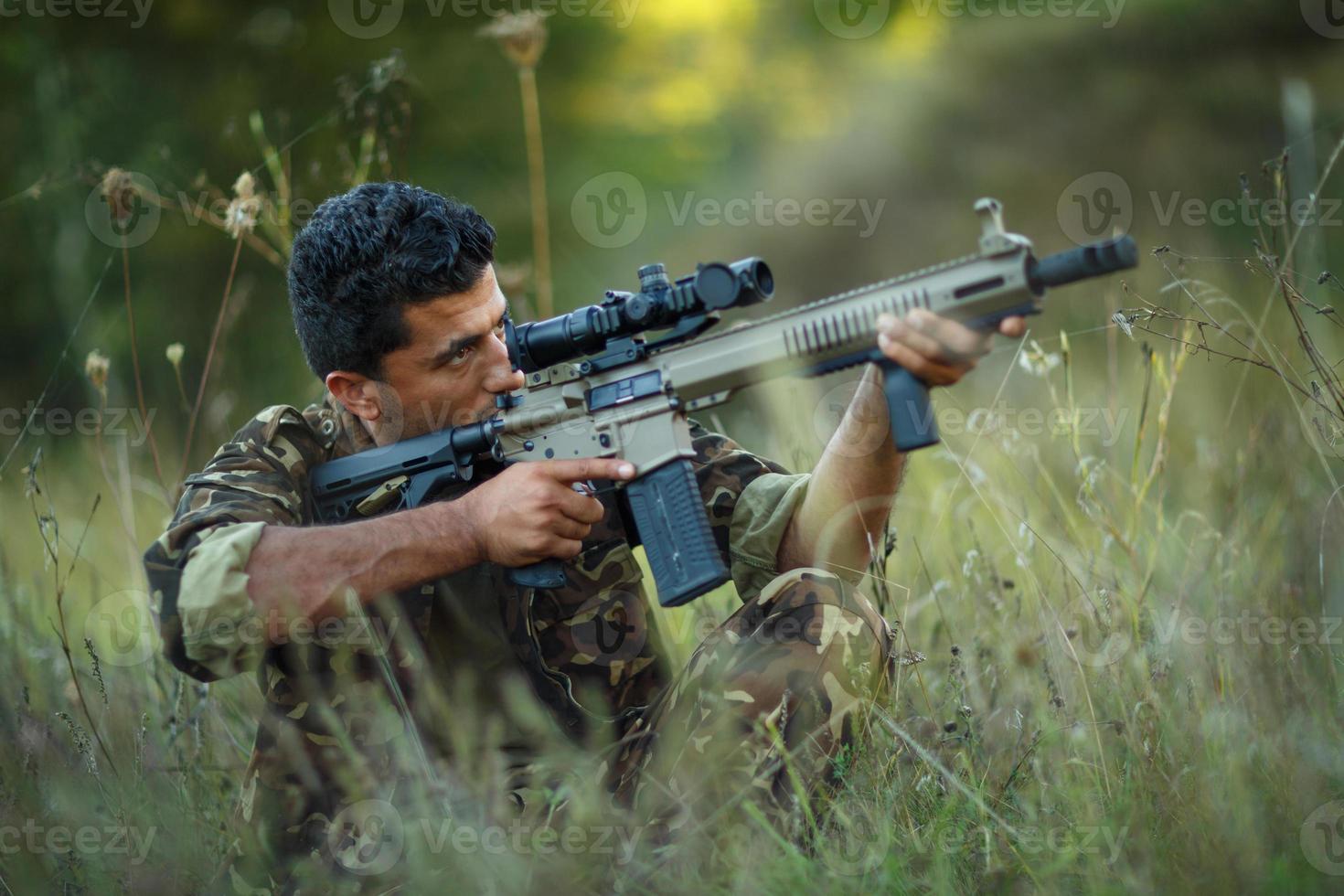 Man of Arab nationality in camouflage with a gun aiming at a target photo