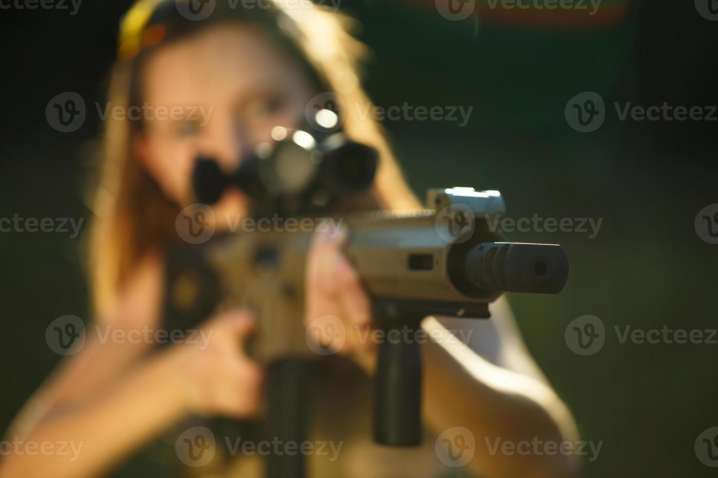 Girl with a gun for trap shooting aiming at a target photo