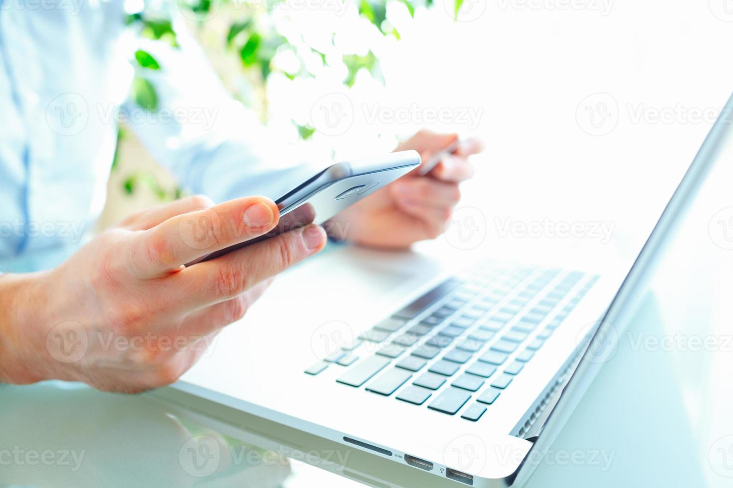 Men office worker typing on the keyboard and using smartphone photo