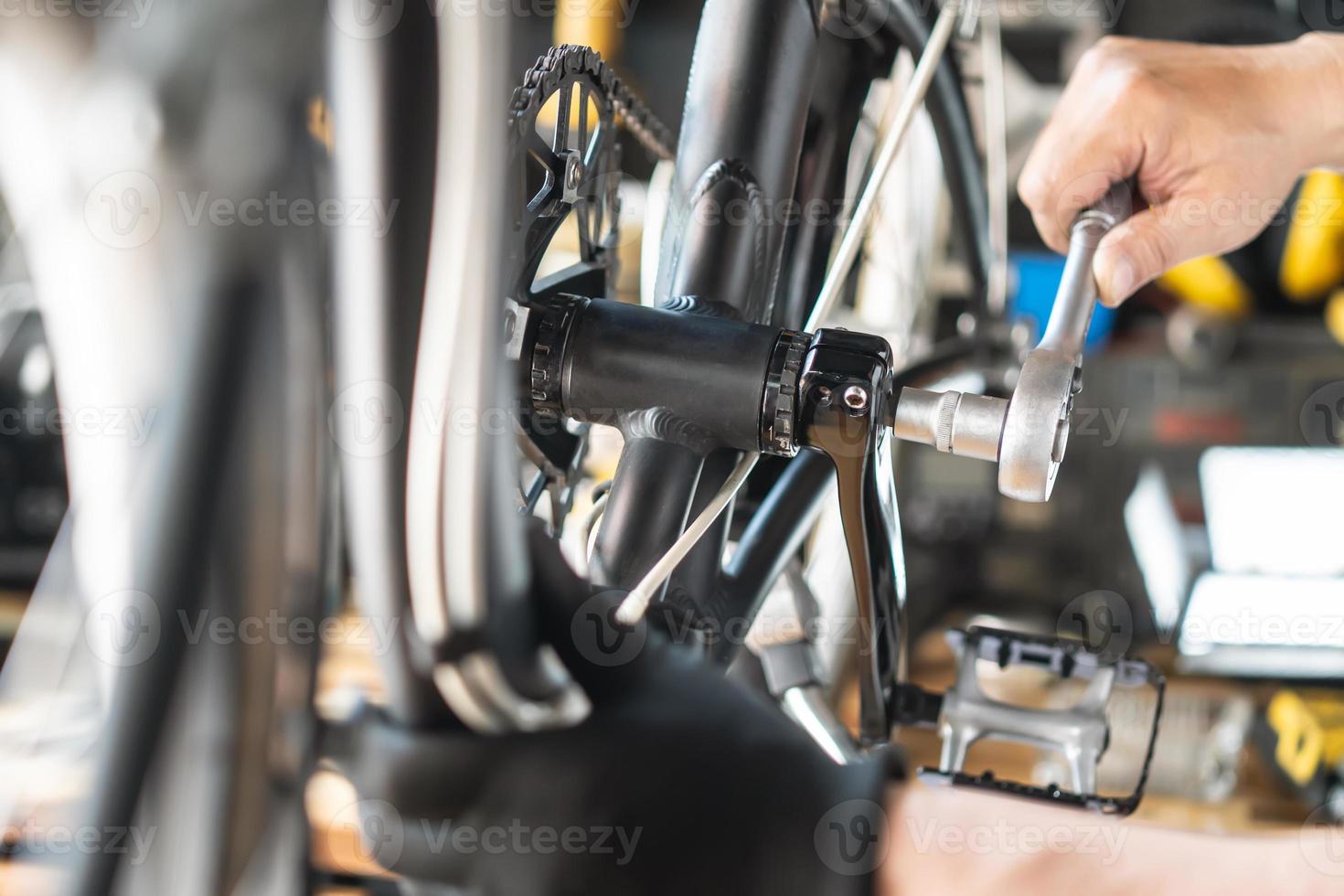 técnico hace ajustes a bielas en un plegable bicicleta trabajando en taller , bicicleta reparar y mantenimiento concepto foto