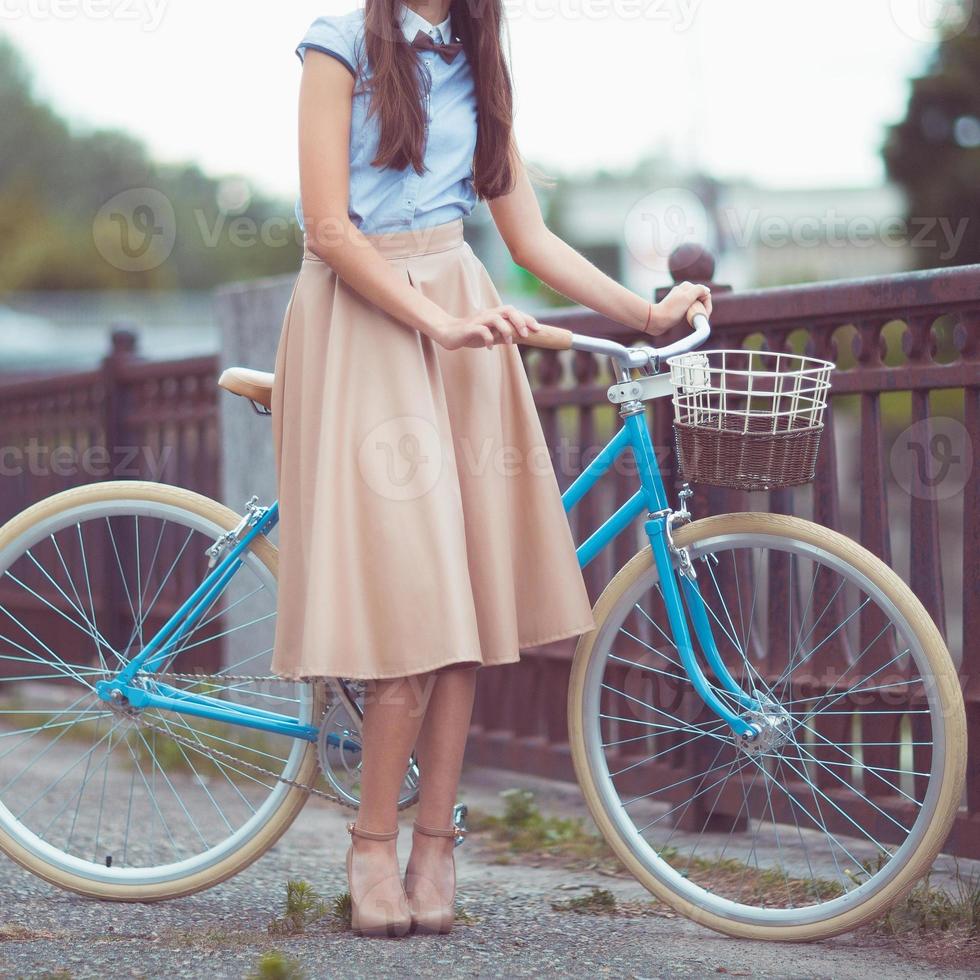 joven bella mujer, elegantemente vestida con bicicleta. belleza, moda y estilo de vida foto