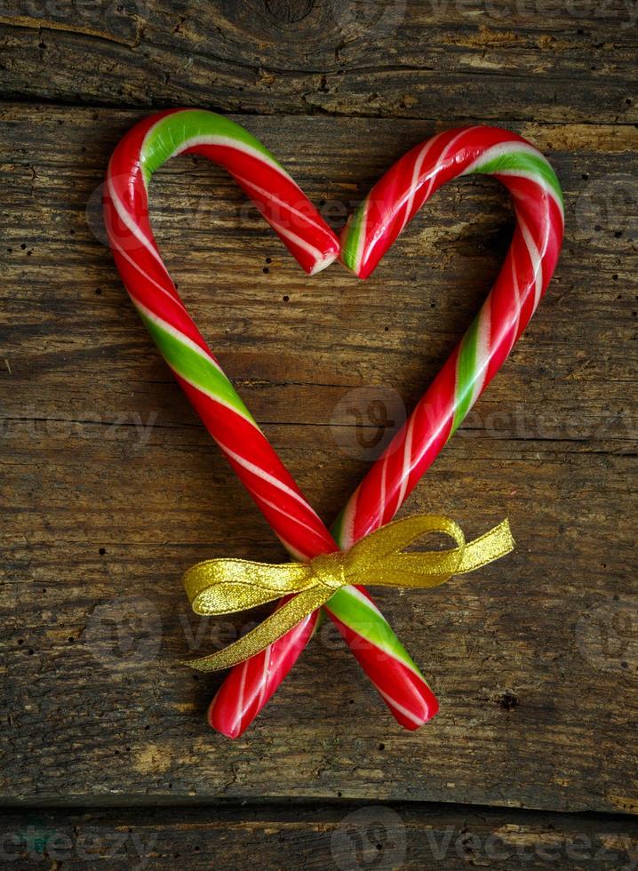 Candy canes in a heart shape on a wooden background photo