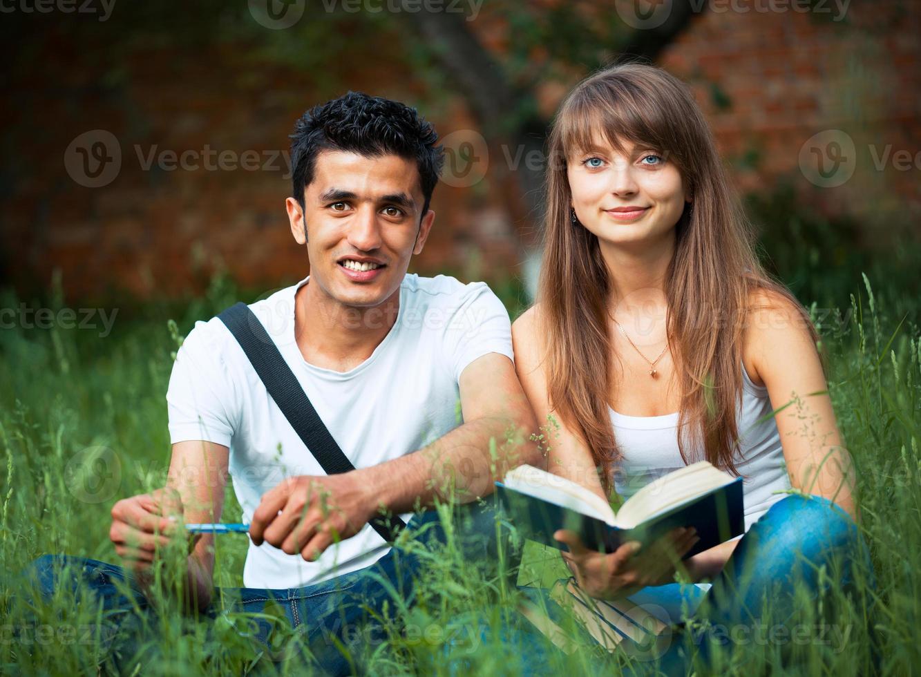 Two students studying in park on grass photo