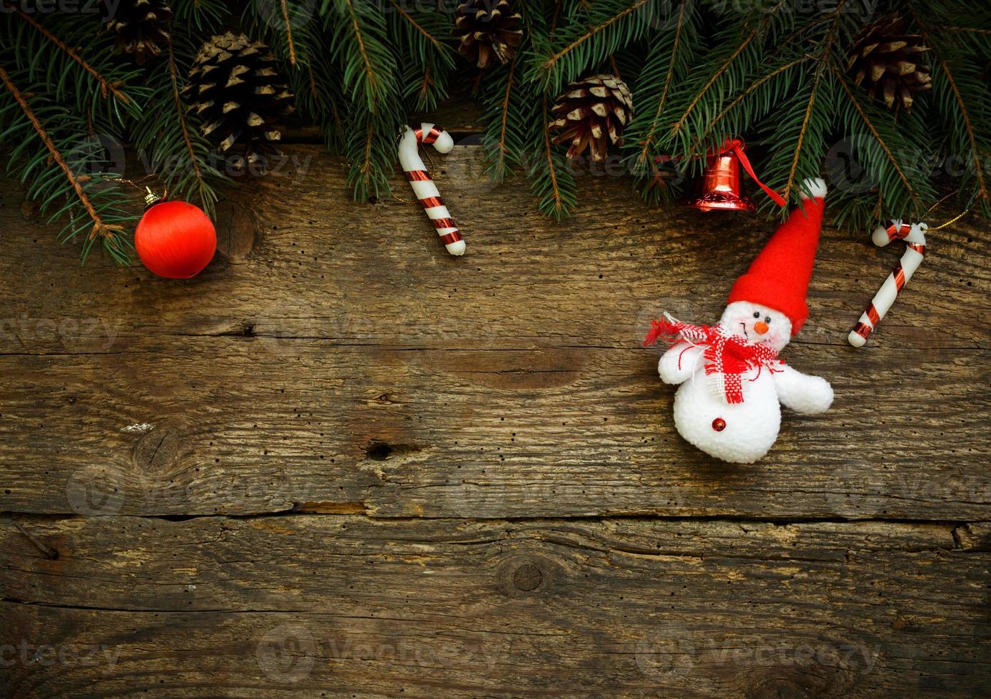 Christmas tree branches with christmas decorations and snowman on wooden texture photo