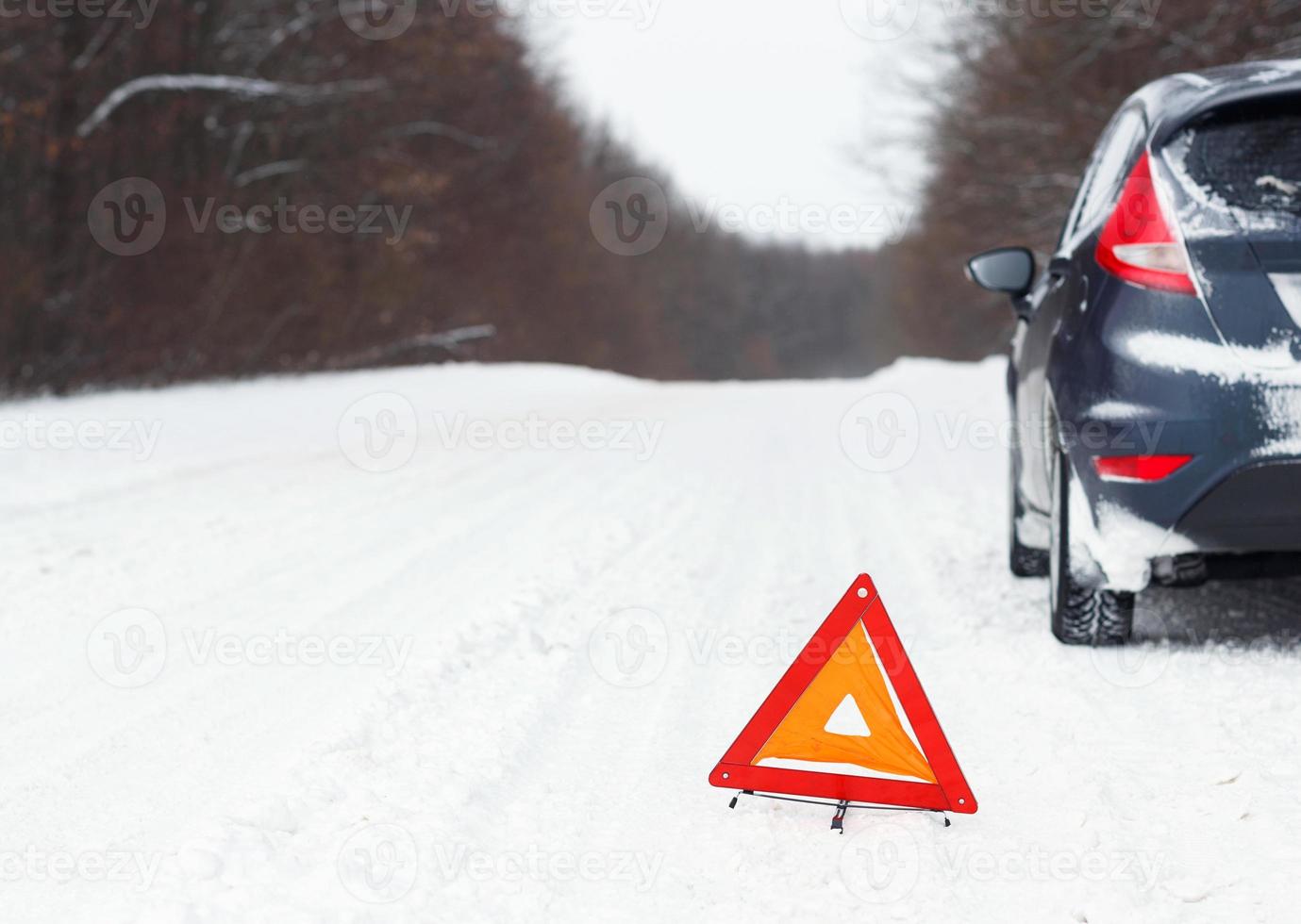 Closeup of red warning triangle with a broken down car photo