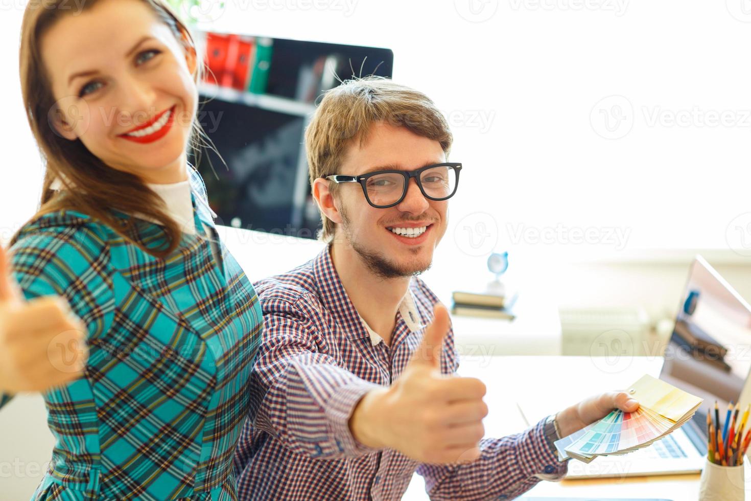 Beautiful young woman and man with thumb up in office photo