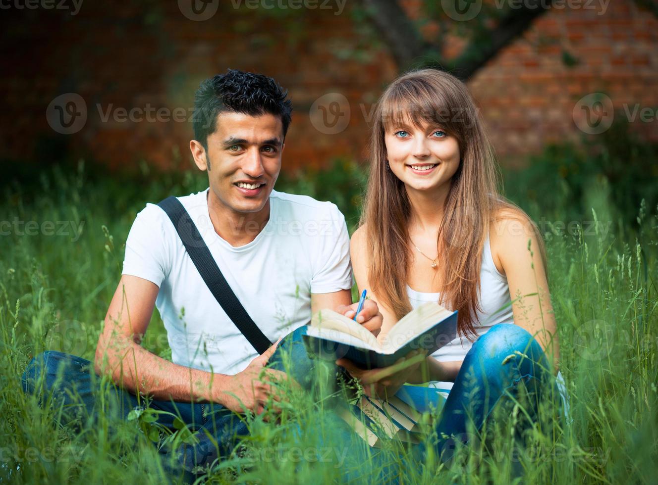 dos estudiantes estudiando en parque en césped con libro al aire libre foto