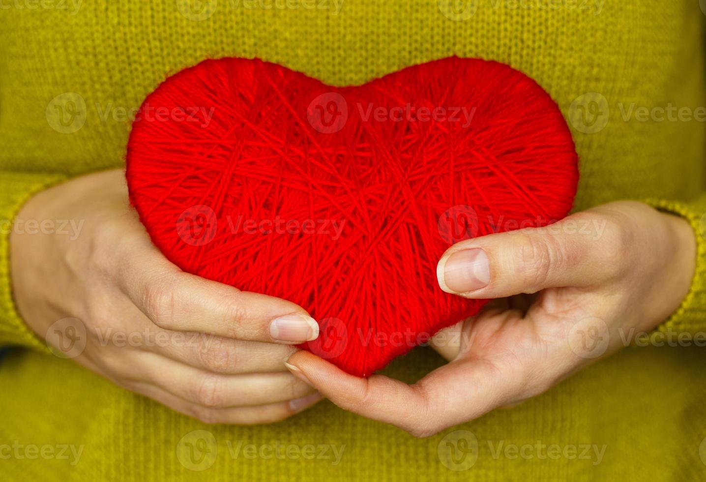 Closeup on red heart made from wool in hand of woman photo