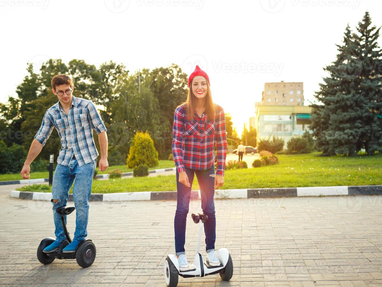 A young couple riding hoverboard - electrical scooter, personal eco transport, gyro scooter, smart balance wheel photo