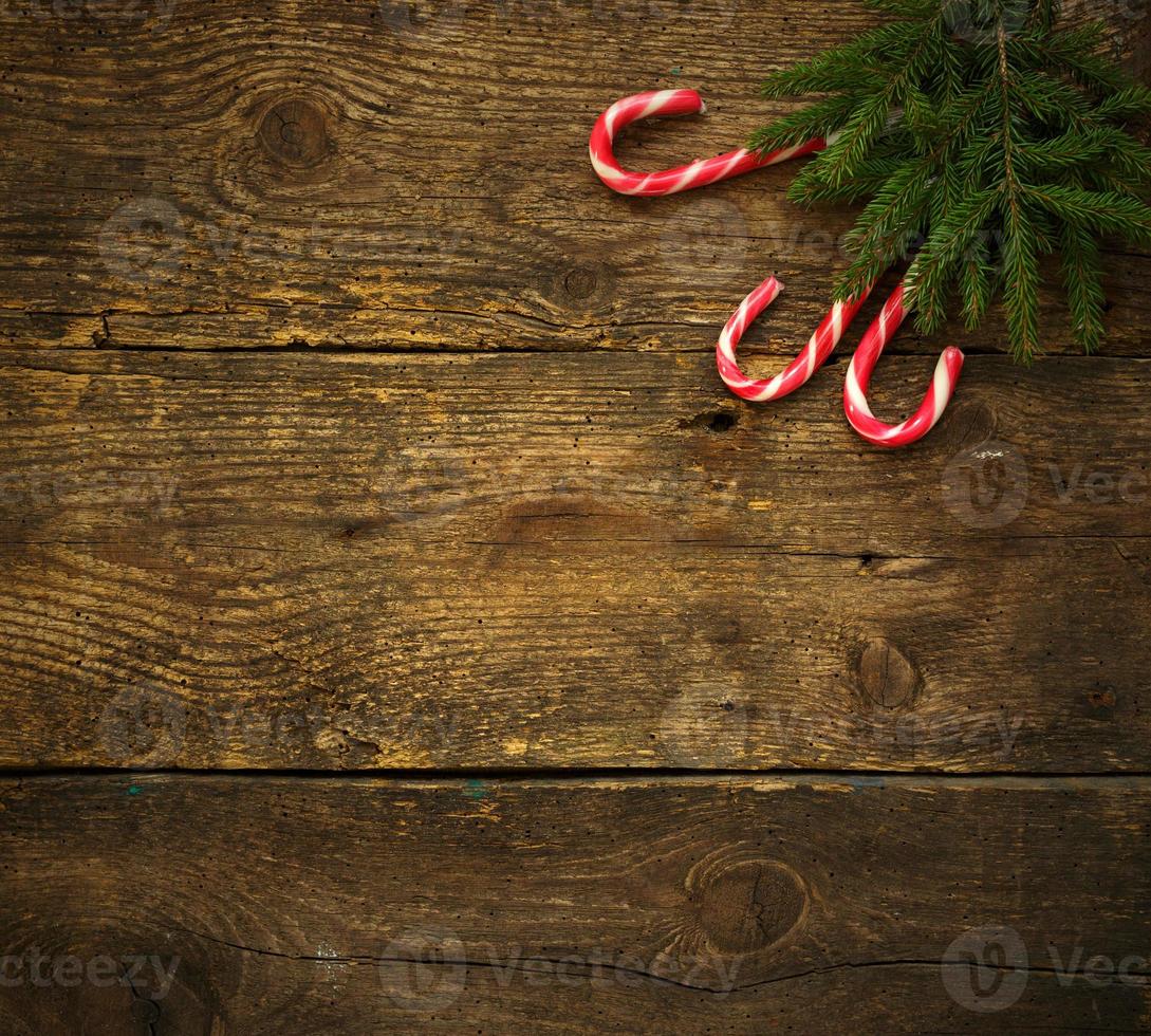 Christmas tree branches with candy canes on wooden texture ready for your design photo
