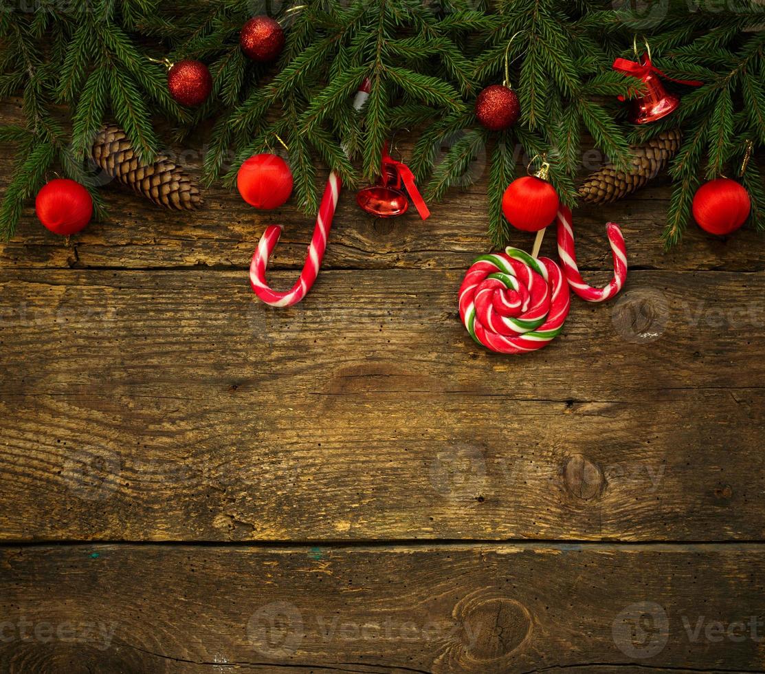 Christmas border with fir tree branches, cones, christmas decorations and candy cane on rustic wooden boards photo