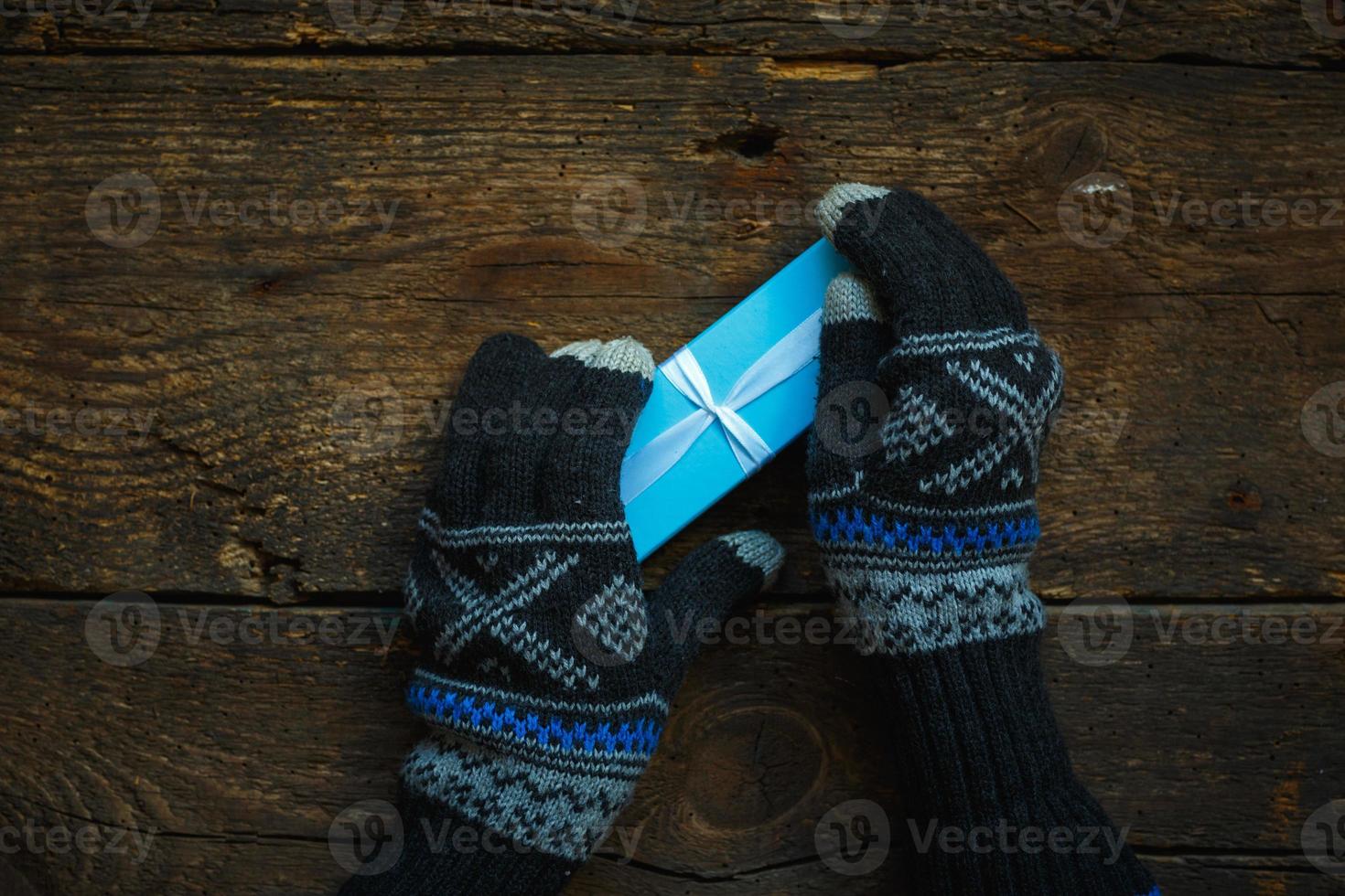 manos en guantes de invierno con caja de regalo de navidad foto