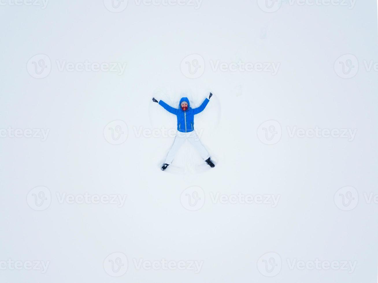 Aeriel view from the drone on woman making snow angels and playing in snow photo