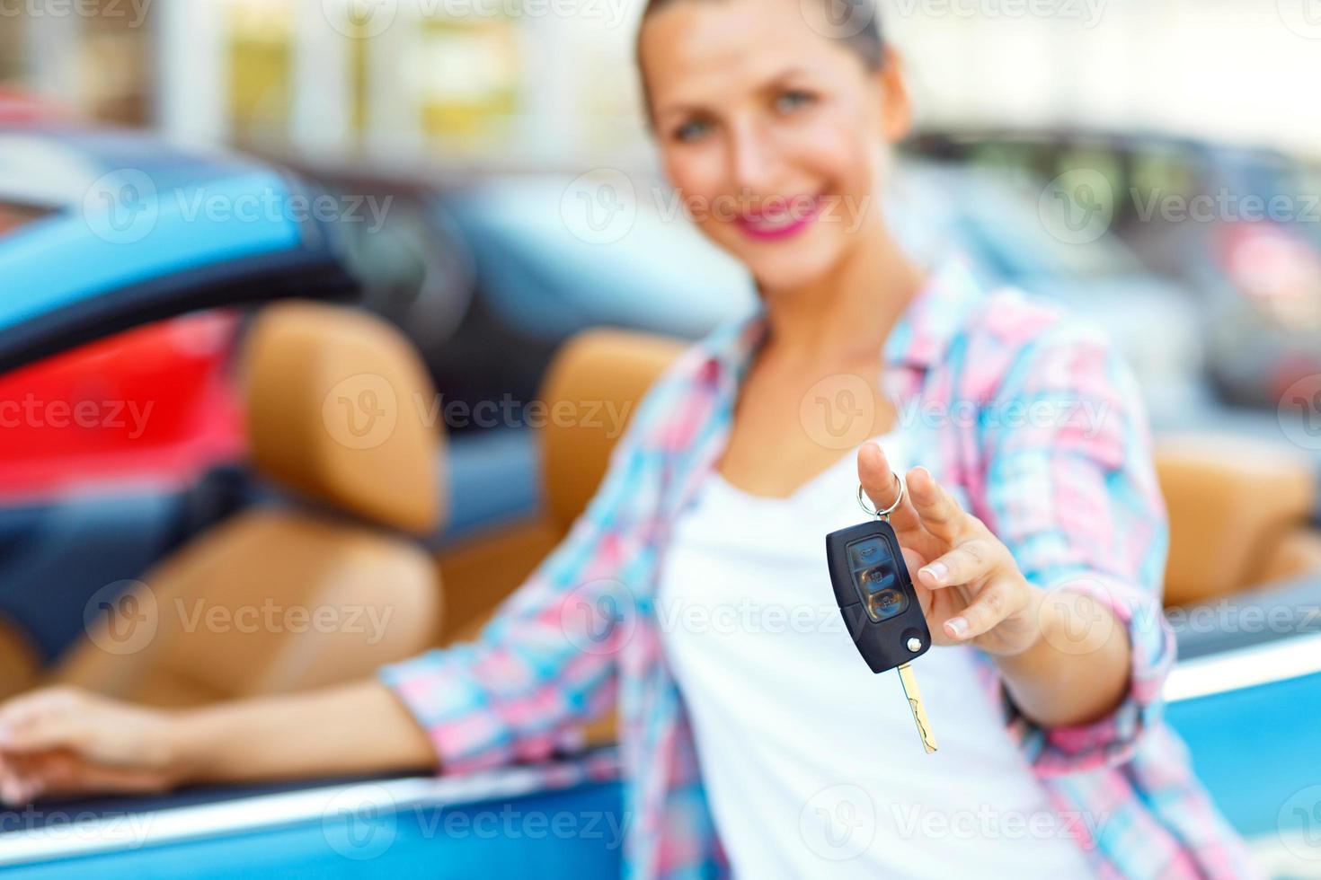 Young woman standing near a convertible with keys in hand photo