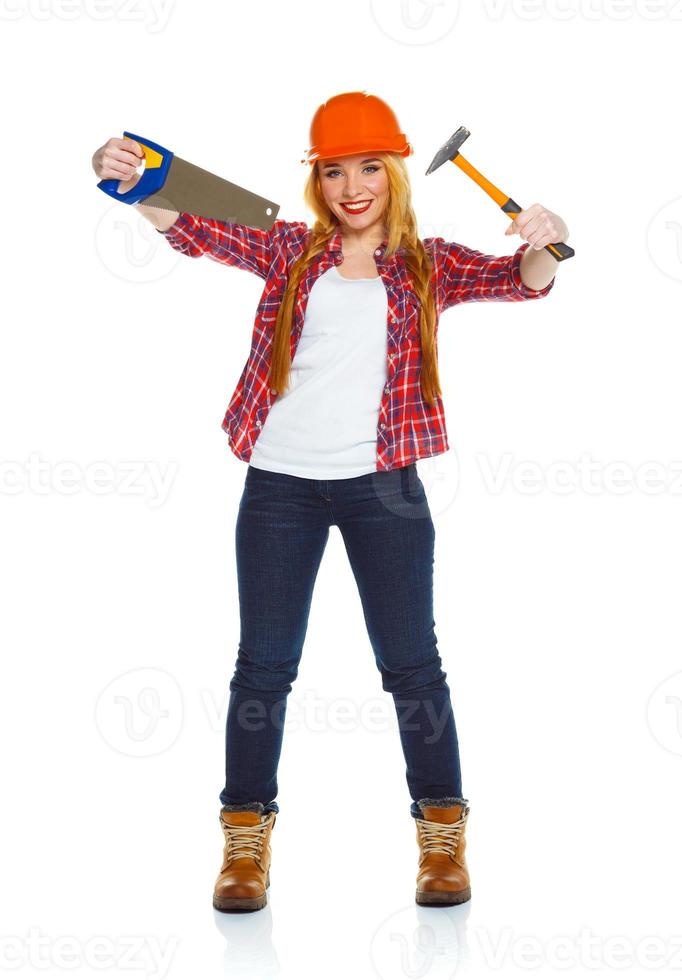 Young woman in helmet with a saw and hammer on a white photo