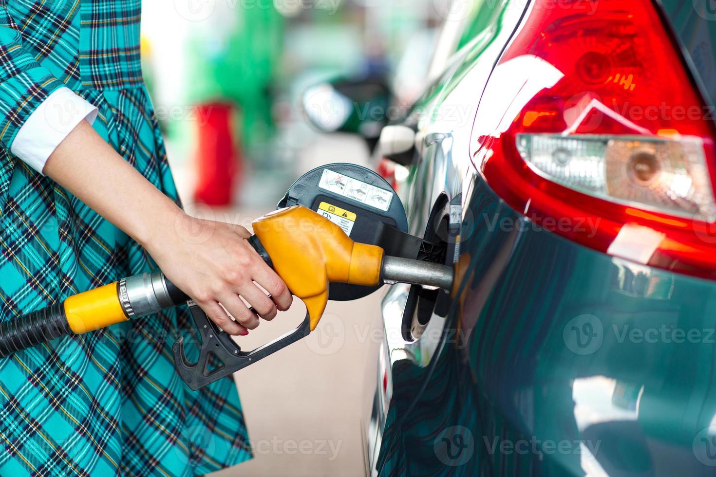 Woman fills petrol into the car at a gas station photo