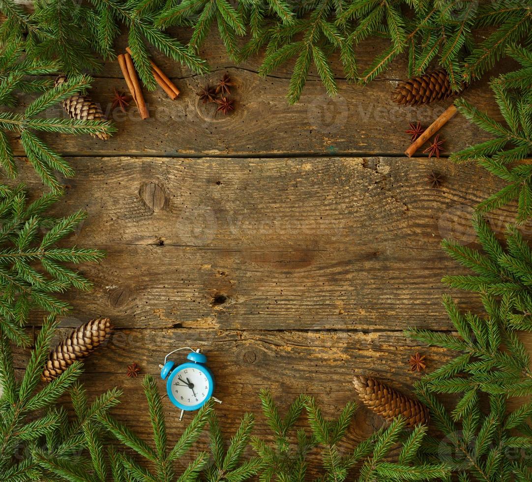 Christmas tree branch with cones, cinnamon, dittany and blue alarm on wooden background with copyspace photo